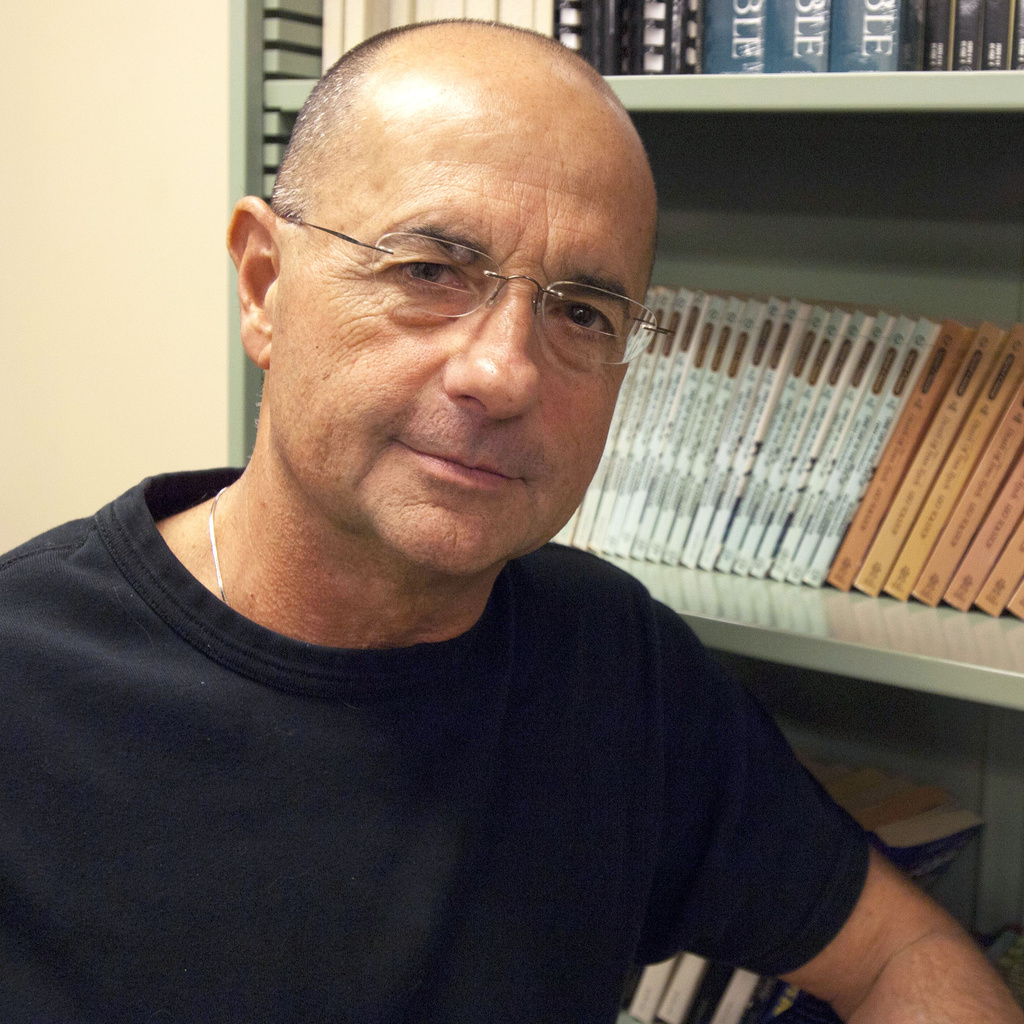 Professor Jay Holstein poses in front of a bookshelf
