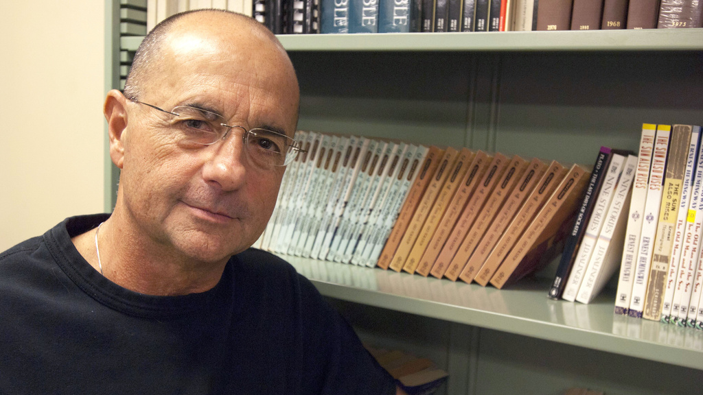 Professor Jay Holstein poses in front of a bookshelf